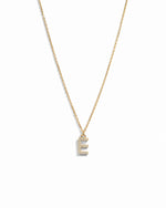 Dainty gold studded initial letter pendant necklace on white background