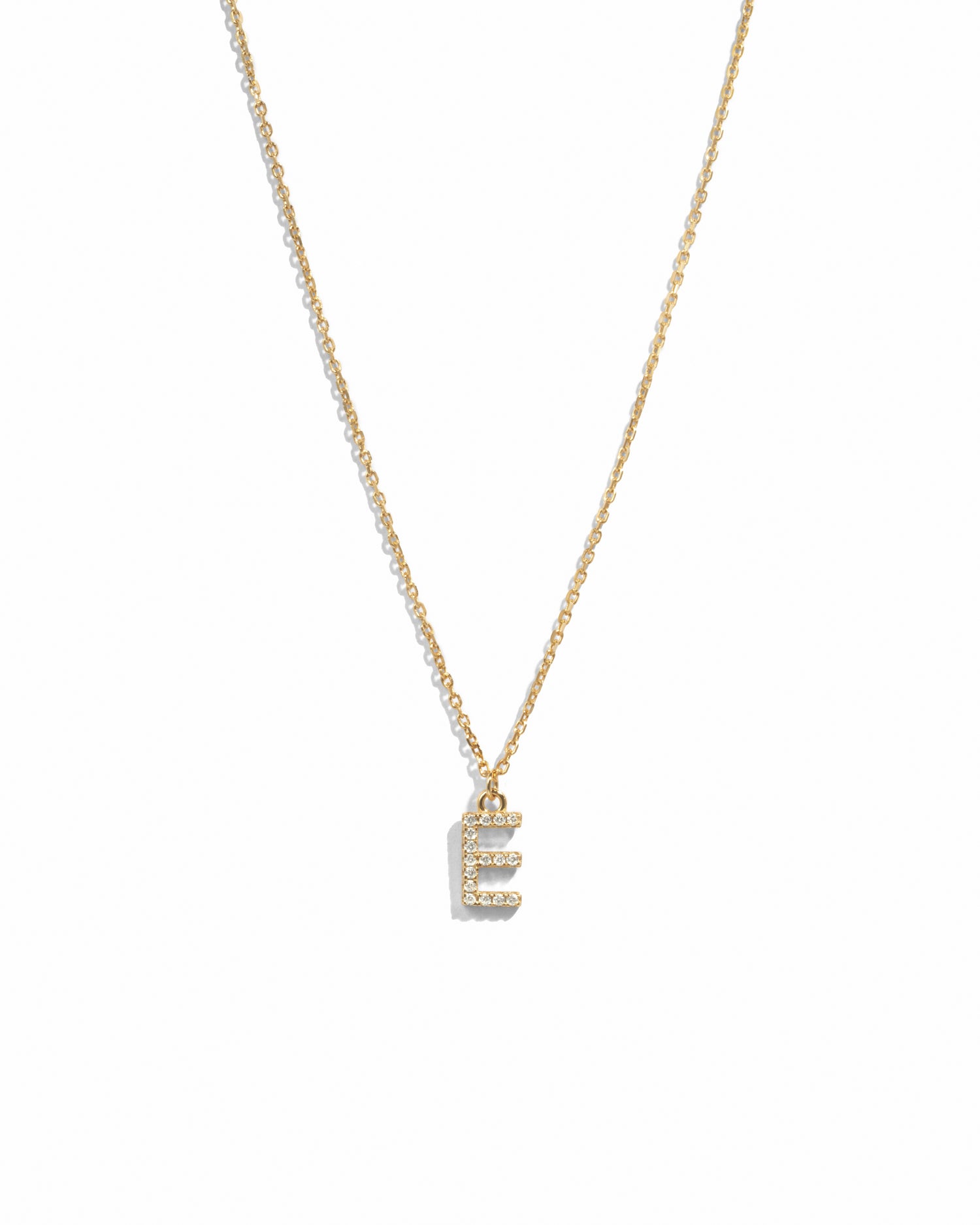 Dainty gold studded initial letter pendant necklace on white background