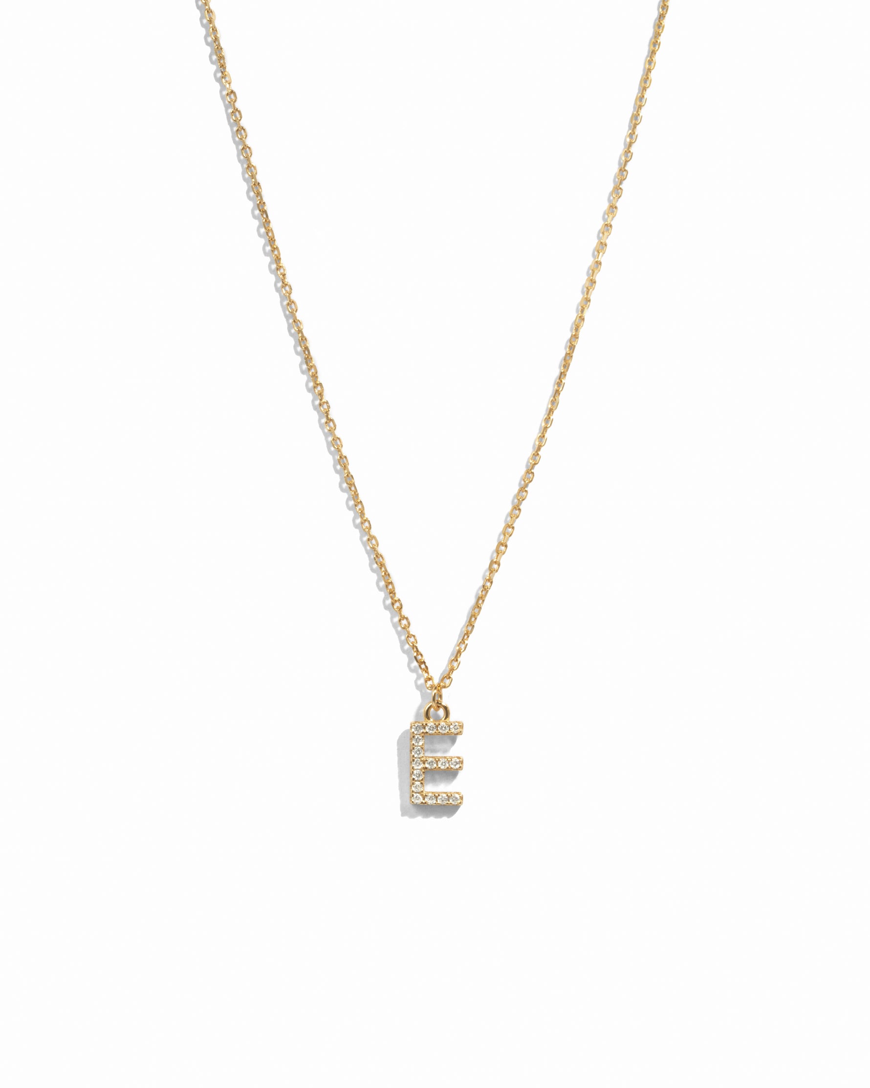 Dainty gold studded initial letter pendant necklace on white background