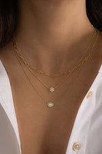 Model wearing gold paperclip chain necklace with a flower opal pendant necklace and an oval opal pendant necklace.