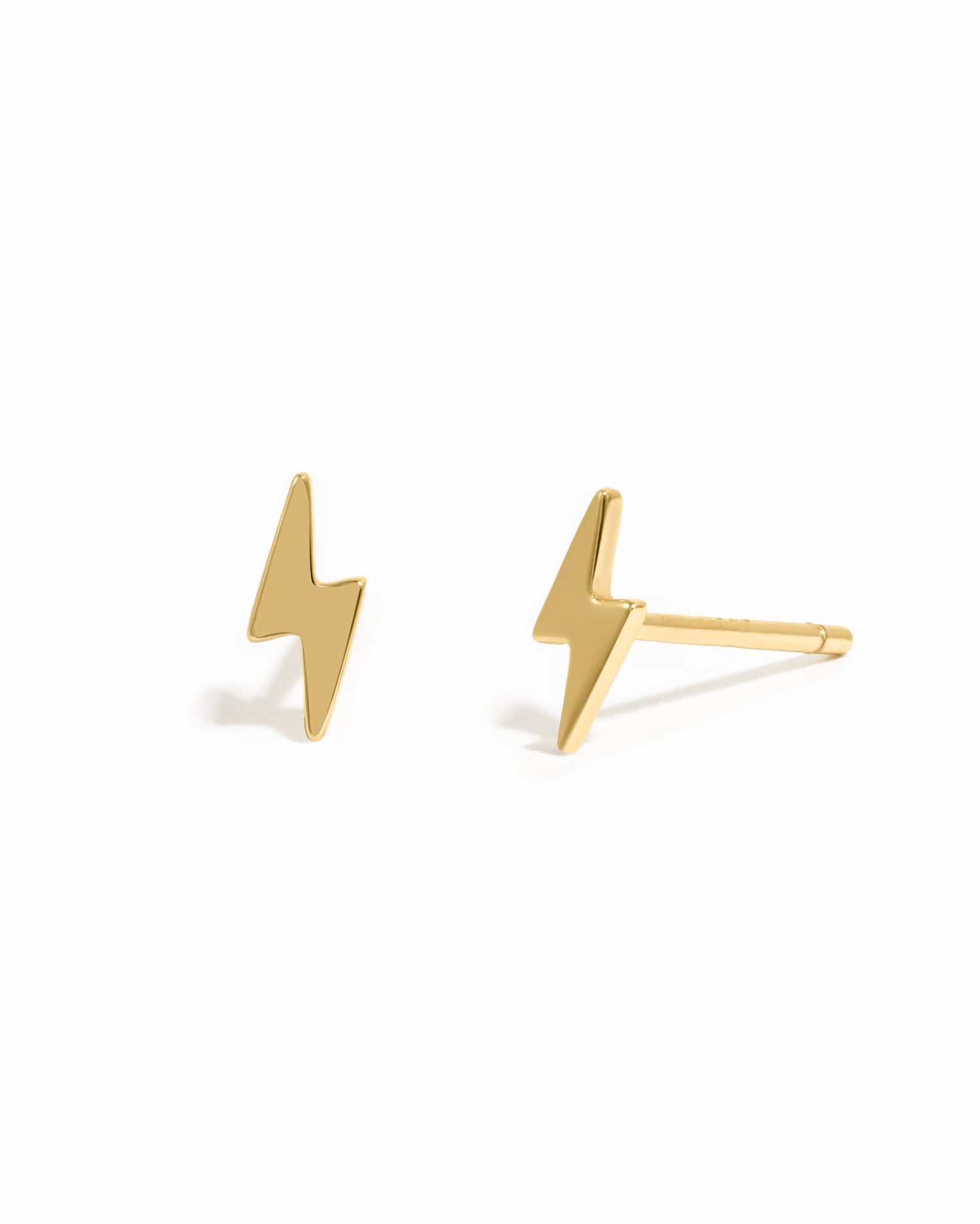 Dainty gold lightning bolt stud earrings on white background.
