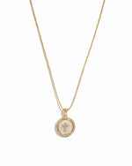 Gold mother of pearl circle cross pendant necklace on a white background.