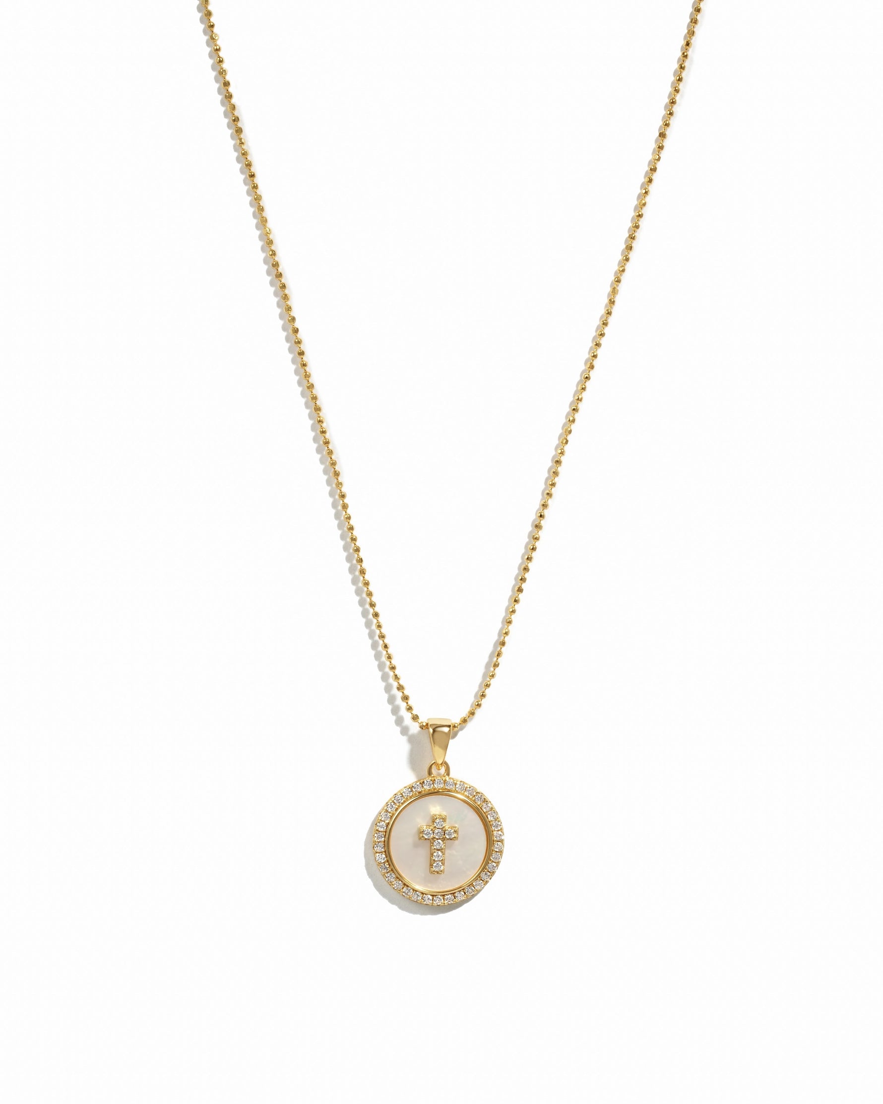 Gold mother of pearl circle cross pendant necklace on a white background.