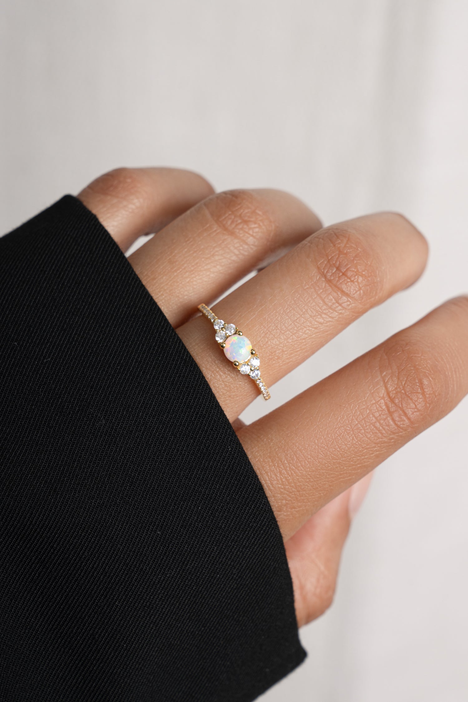 Model wearing delicate gold opal birthstone ring. 