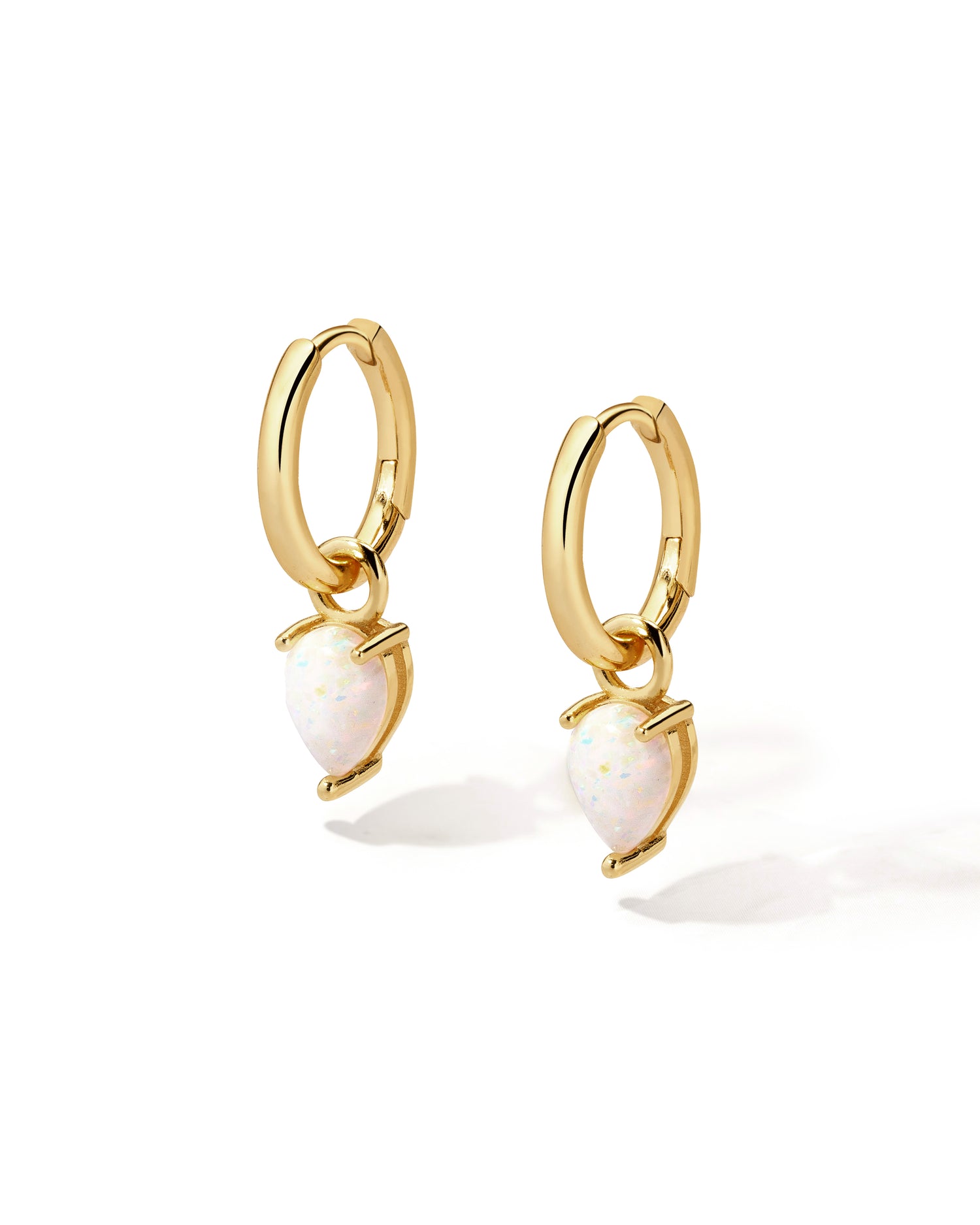 Gold removable opal tear drop charm earrings on white background.