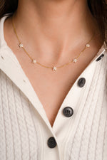 Model wearing diamond flower charm necklace.