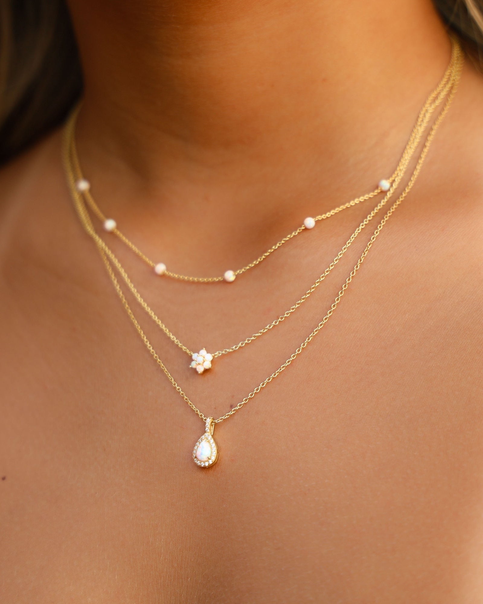 Model wearing delicate gold opal necklace stack.