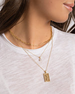 Model wearing dainty gold paperclip necklace with cushion diamond pendant necklace and a rose rectangle medallion gold necklace.