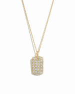 Statement gold pavé dog tag pendant necklace on white background.