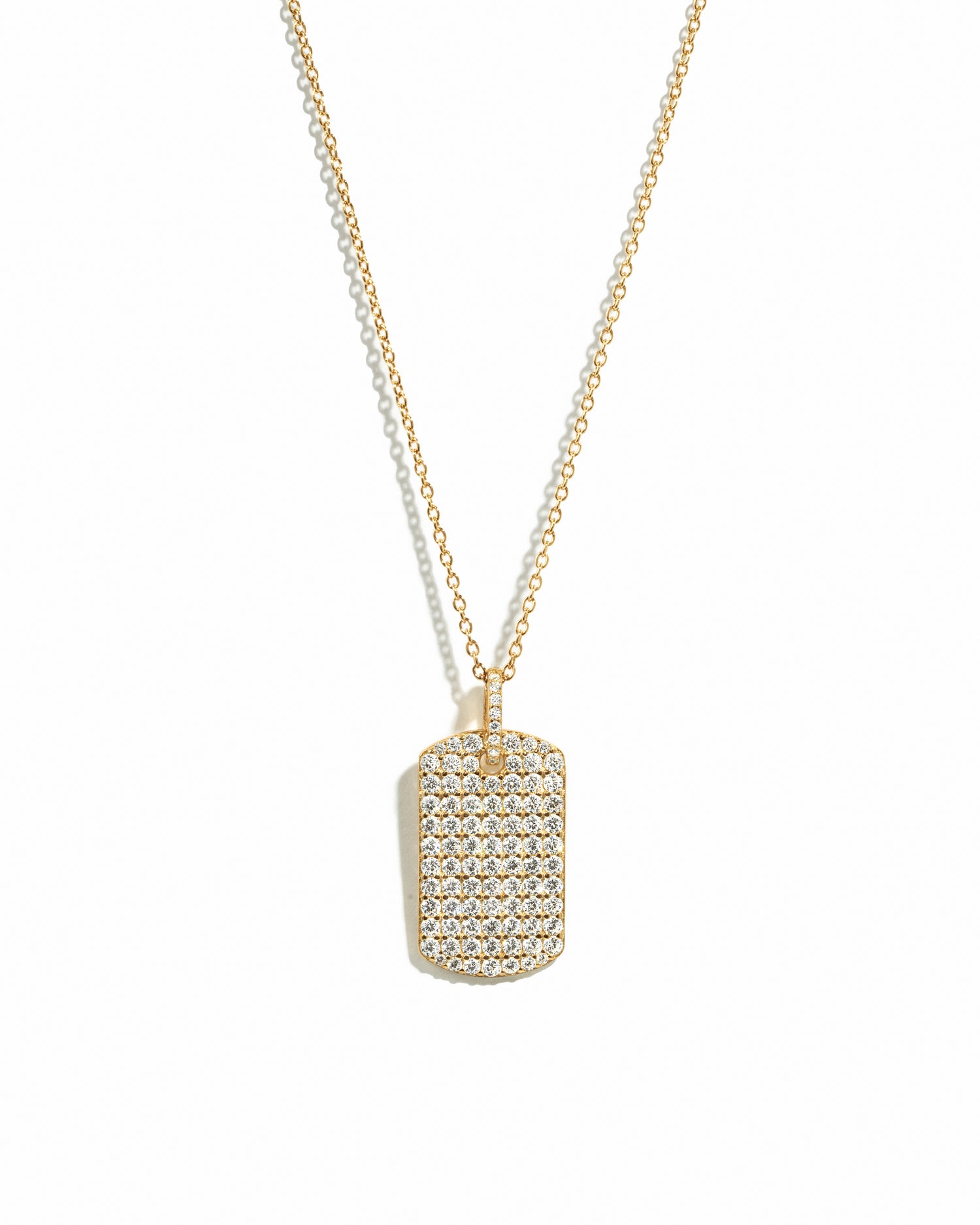 Statement gold pavé dog tag pendant necklace on white background.