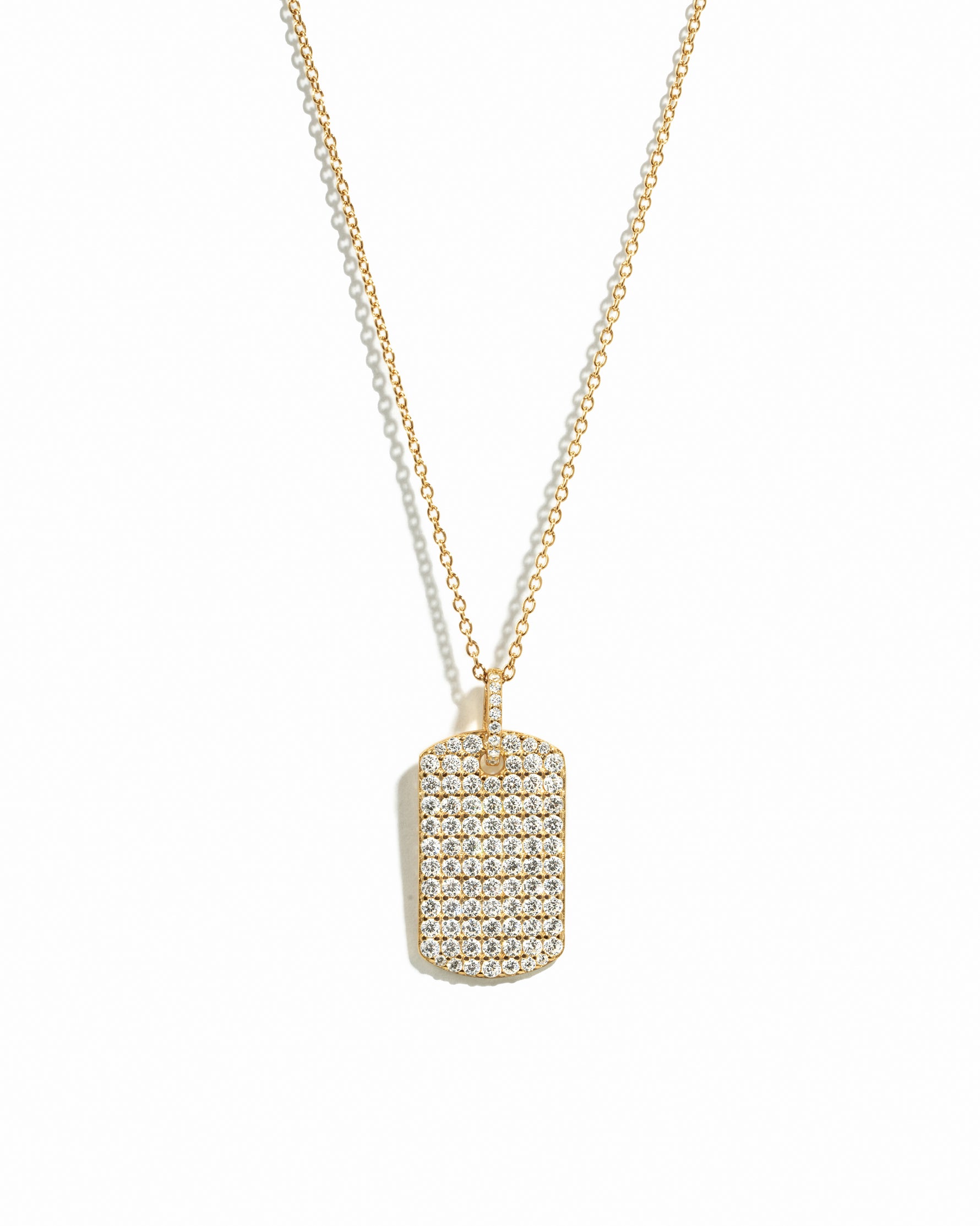 Statement gold pavé dog tag pendant necklace on white background.