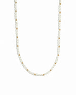 Gold beads and pearl beaded necklace on white background.