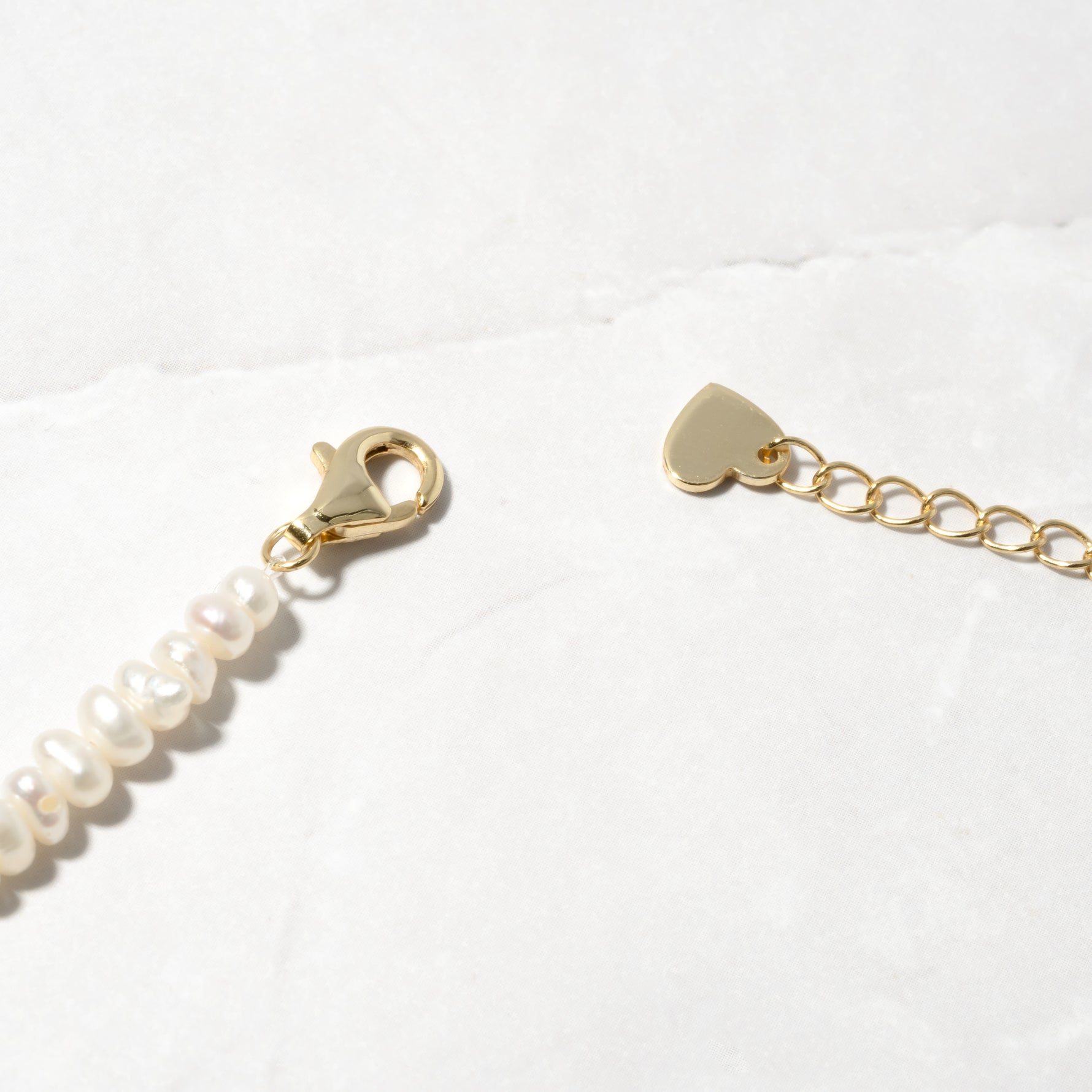 Up-close of gold pearl beaded necklace with lobster clasp. 