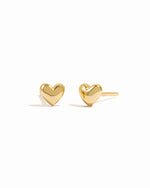 Sleek small gold heart stud earrings on white background