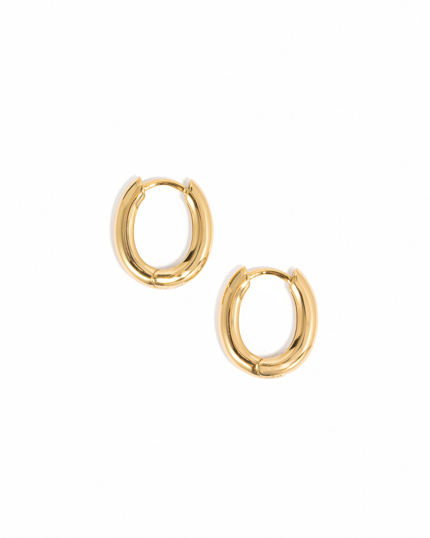 Minimalist oval gold huggie hoops on white background