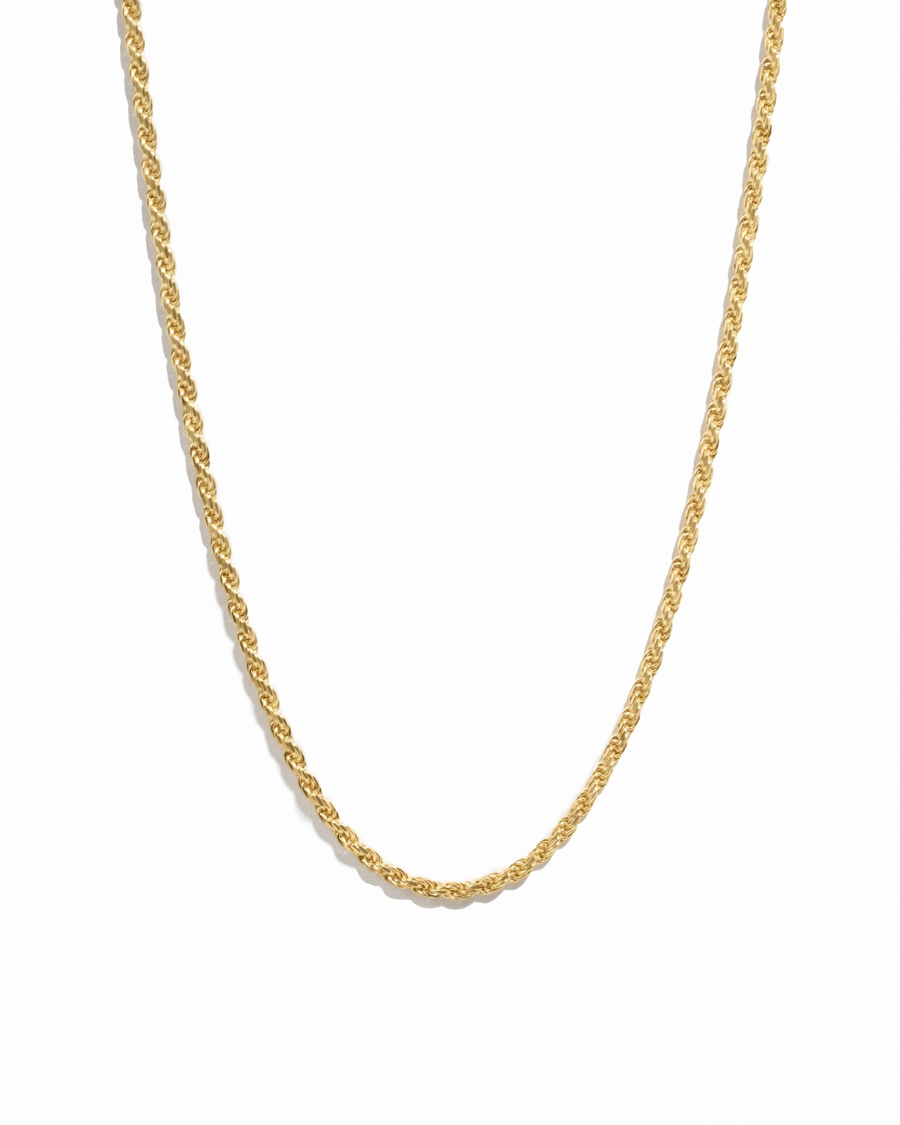 Thin gold rope chain on white background
