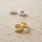 Close up shot of 14k gold plated croissant hoop earrings.