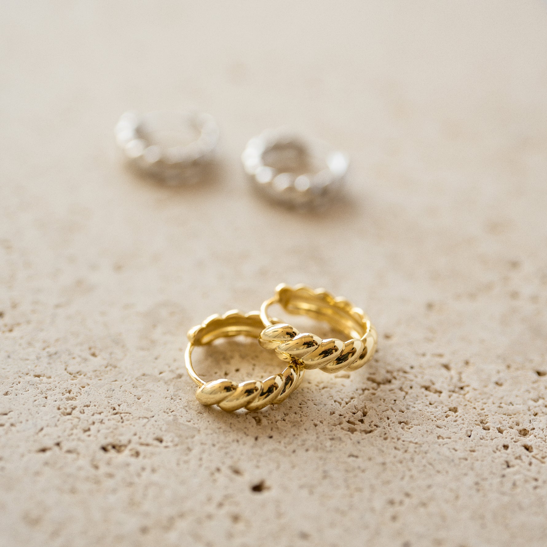 Close up shot of 14k gold plated croissant hoop earrings.