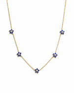 Minimalist gold sapphire flower charm necklace on white background