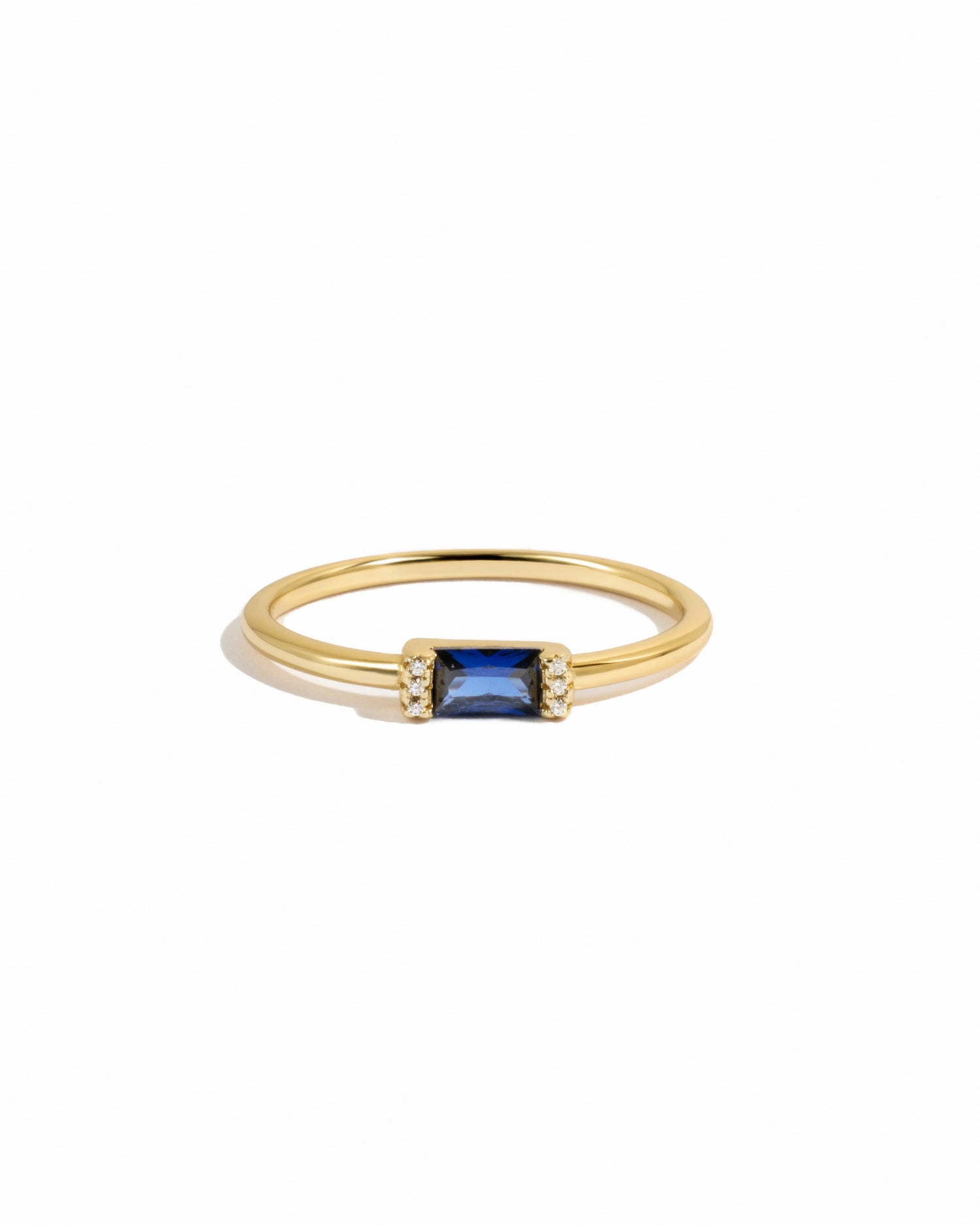 Gold ring with a sapphire gemstone on a white background