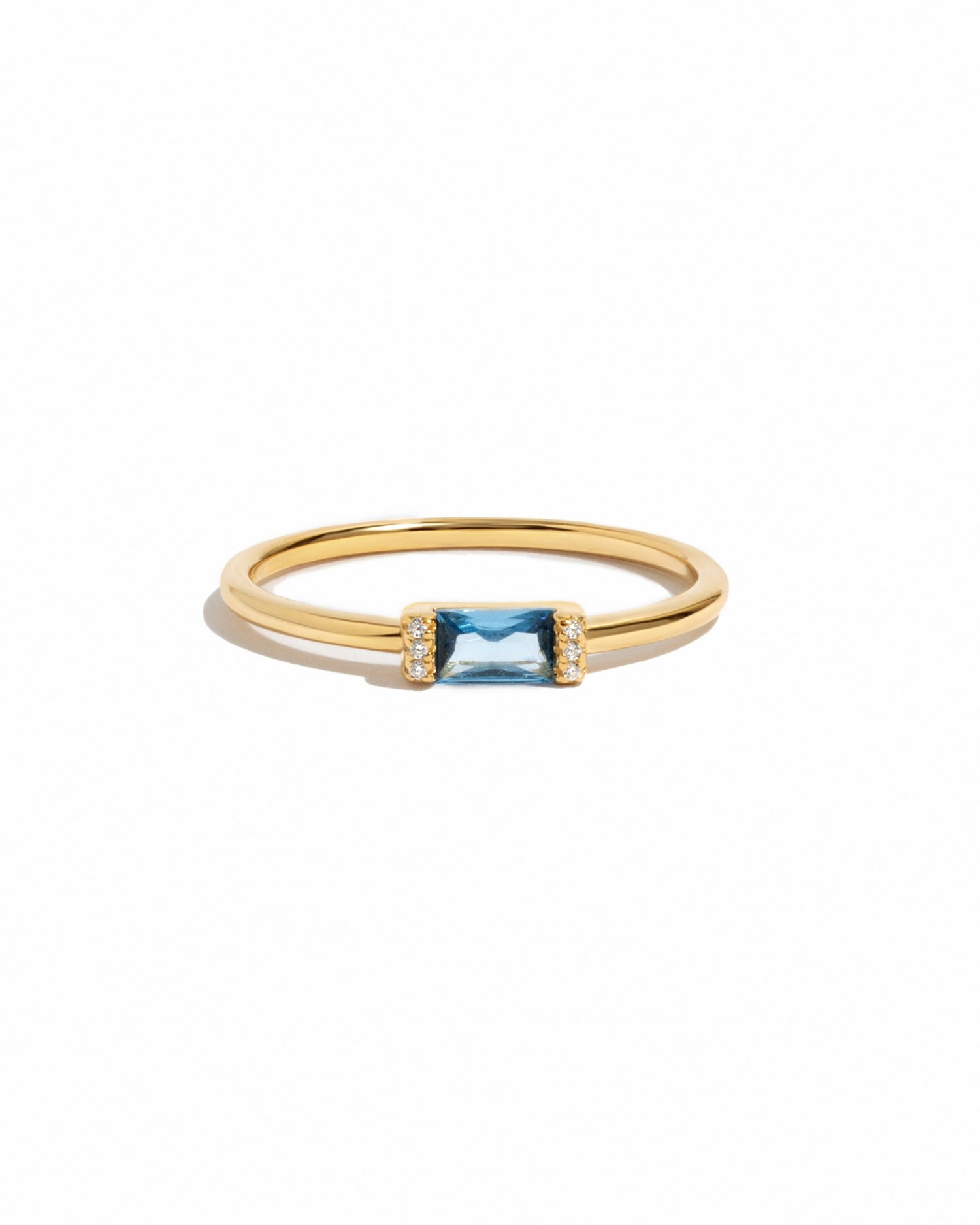 Delicate gold aquamarine gemstone ring on white background.