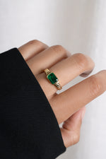 Model wearing gold emerald statement ring with textured band. 