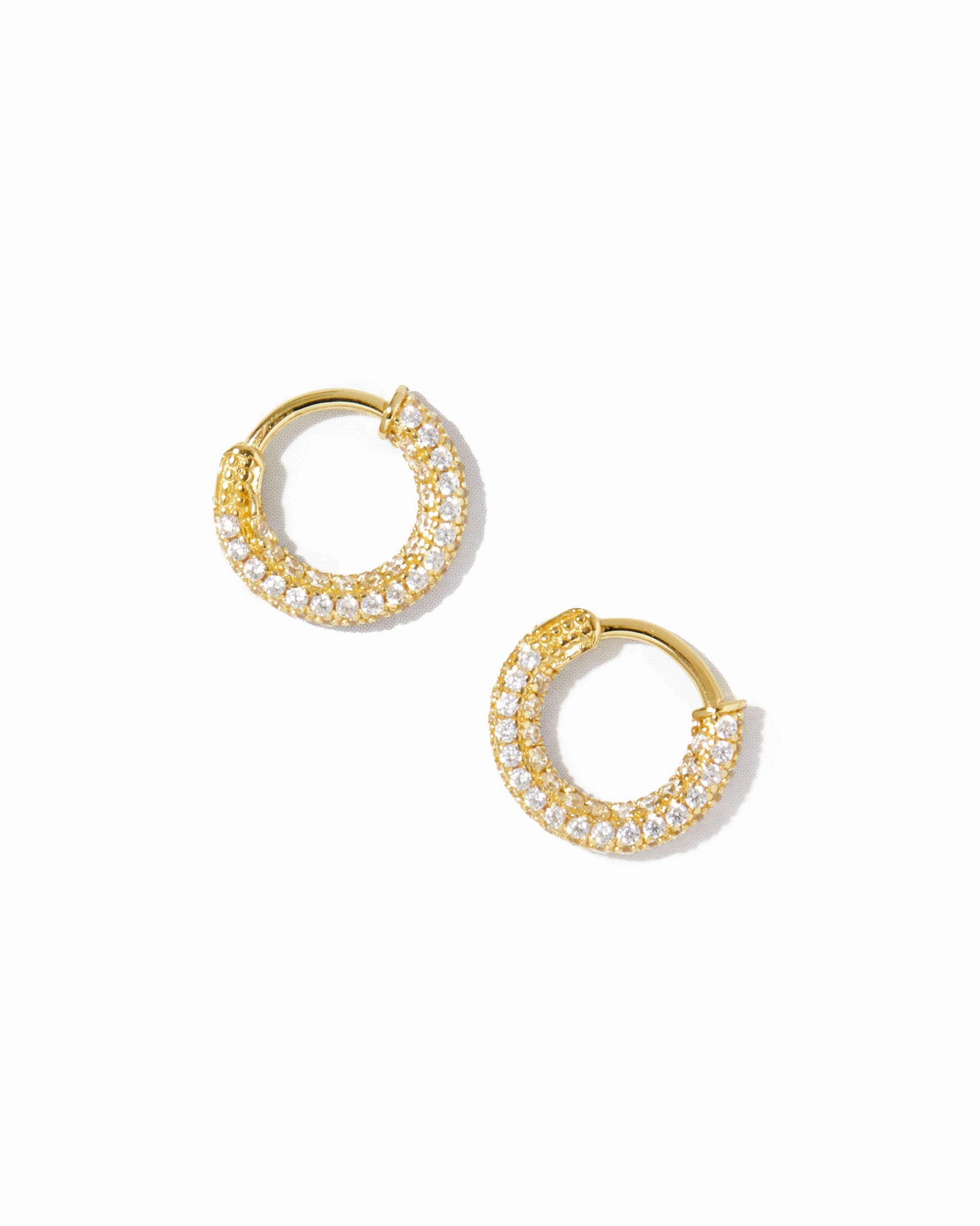 Gold plated diamond studded circular hoop earrings on white background.