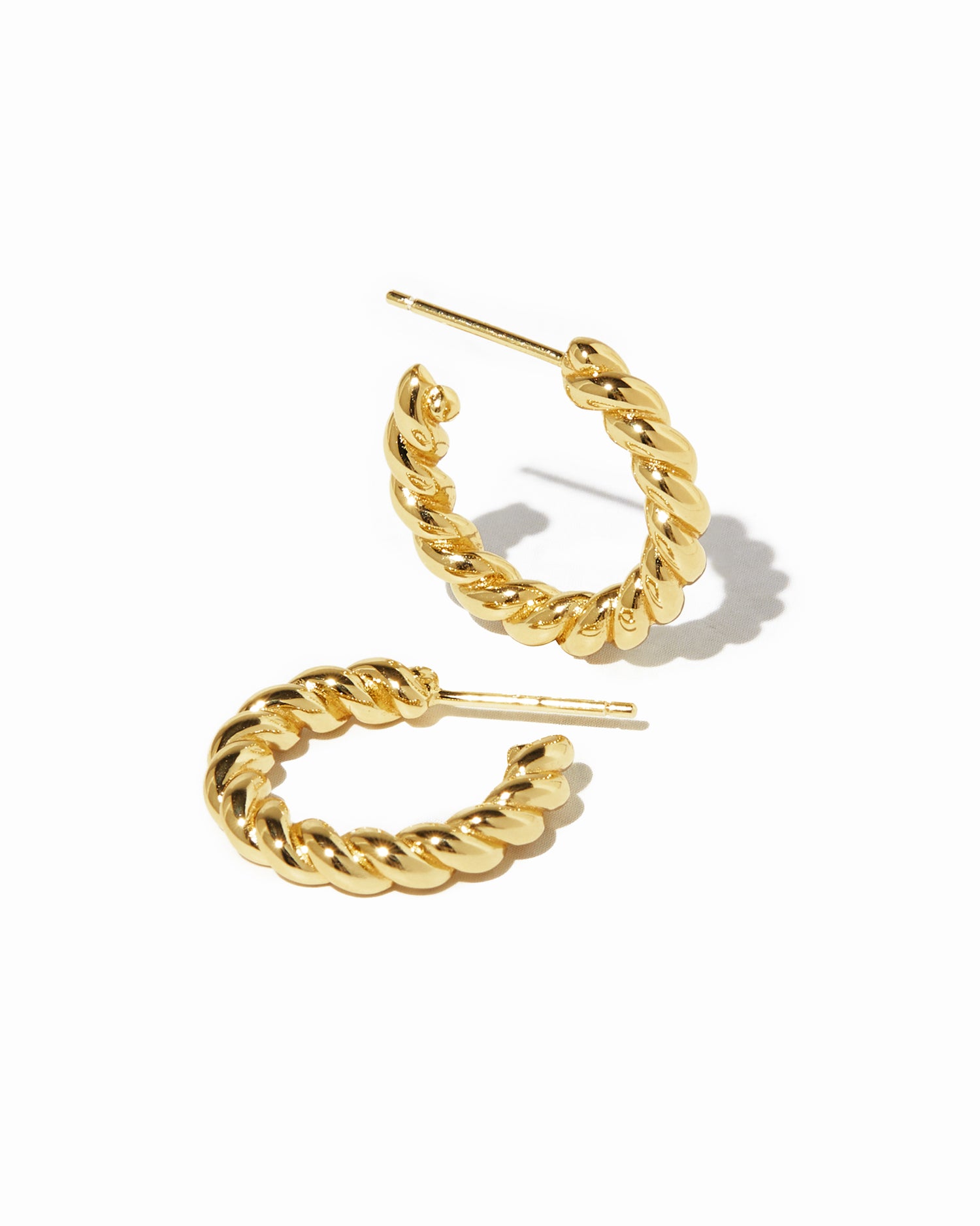 Gold spiral textured hoop earrings on white background