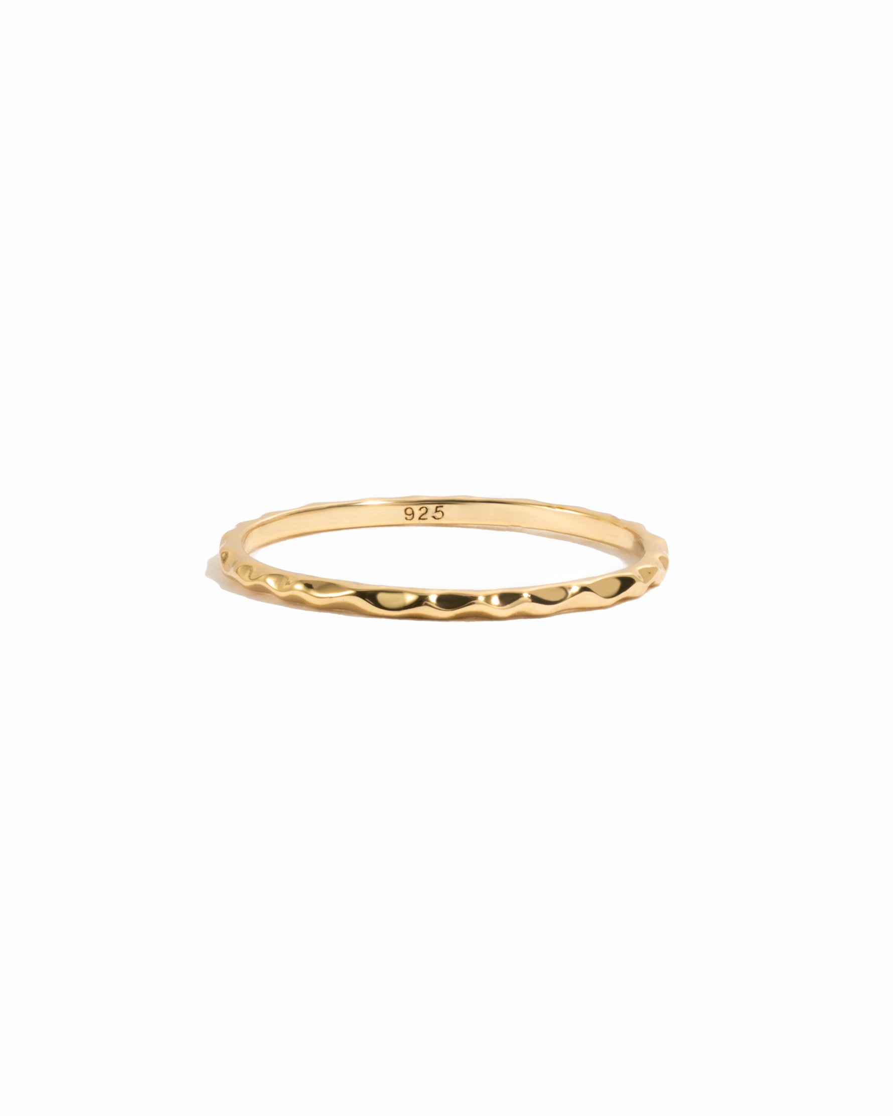 Gold thin plain hammered band on white background.
