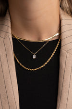 Model wearing herringbone chain necklace, diamond pendant necklace, and chunky rope chain necklace.