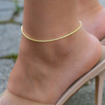 Model wearing yellow gemstone dainty tennis ankle bracelet on model. 