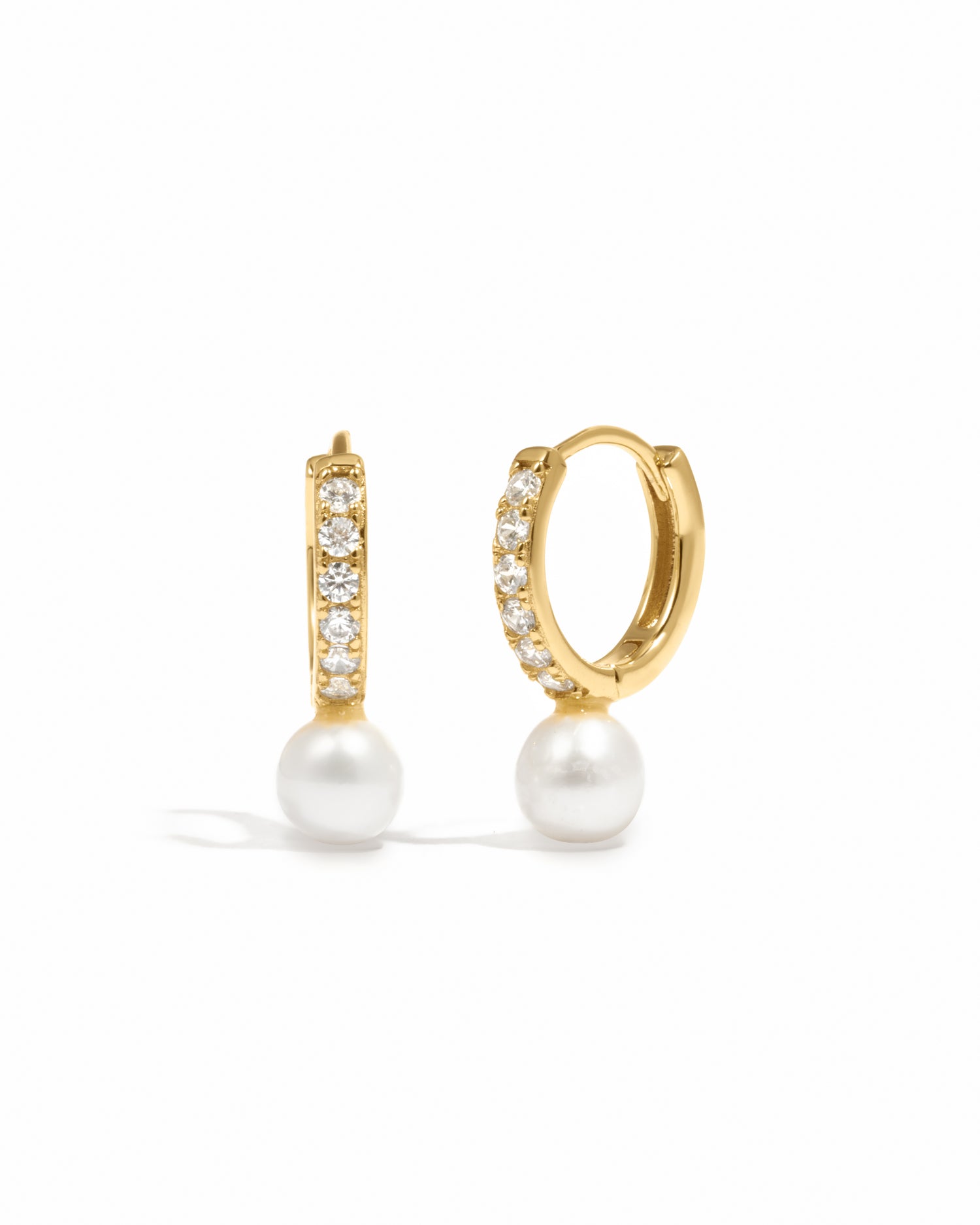 Luxury gold studded diamond pearl charm earrings on white background.