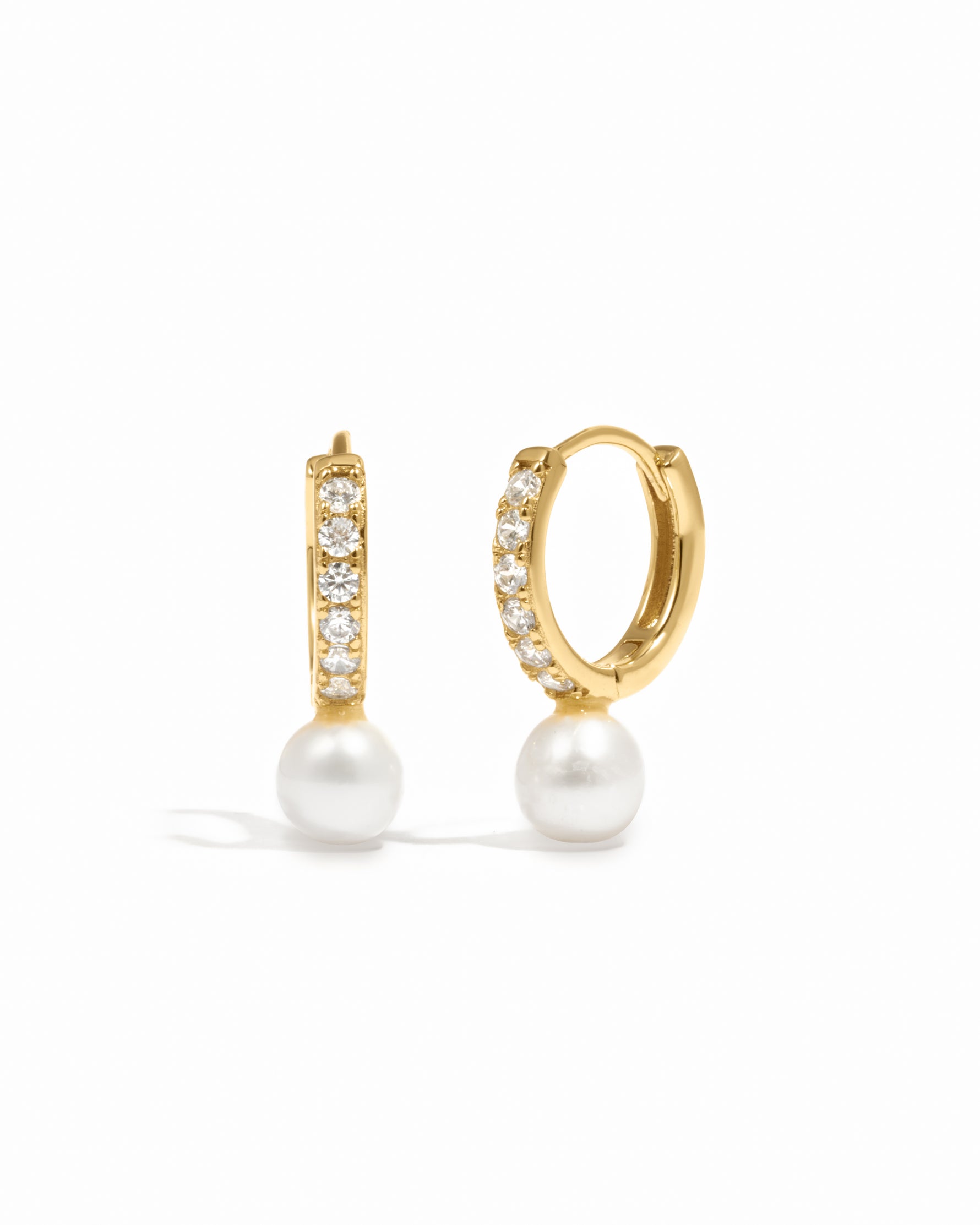 Luxury gold studded diamond pearl charm earrings on white background.