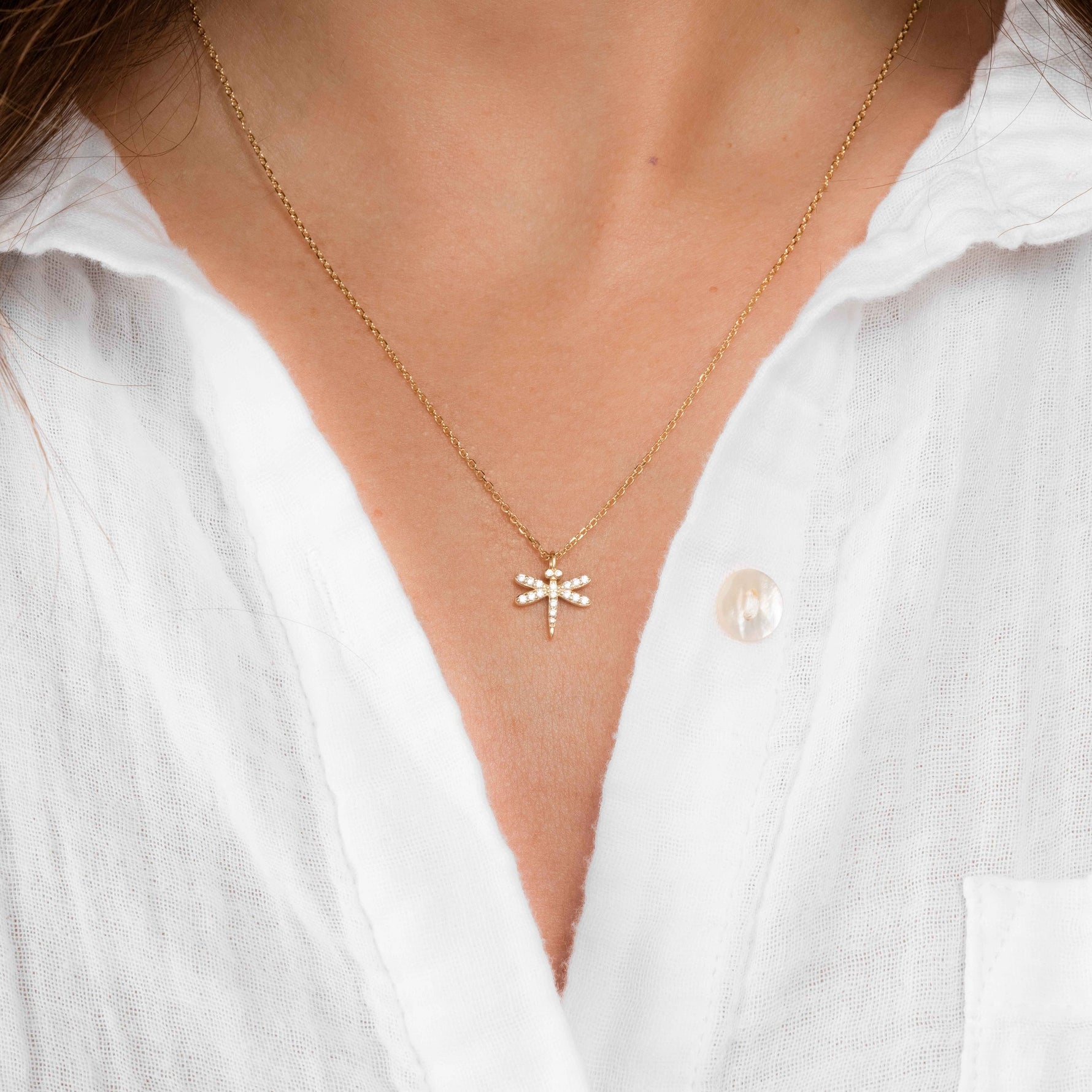 Model wearing delicate gold cz dragonfly necklace. 