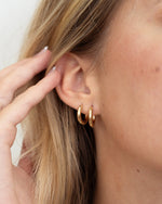 Model wearing two gold minimalist hoop earrings