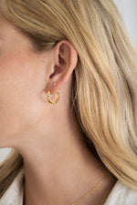 Model wearing gold texture croissant hoops with solitaire stud diamond earrings. 