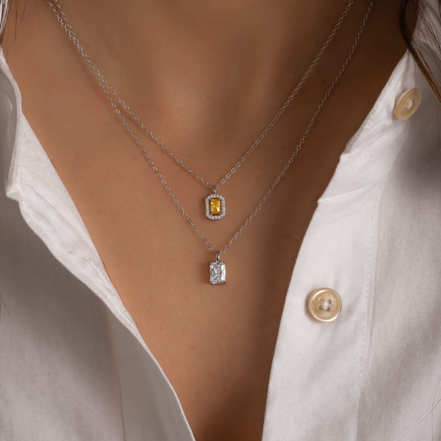 Model wearing silver minimalist diamond baguette necklace in a stack. 