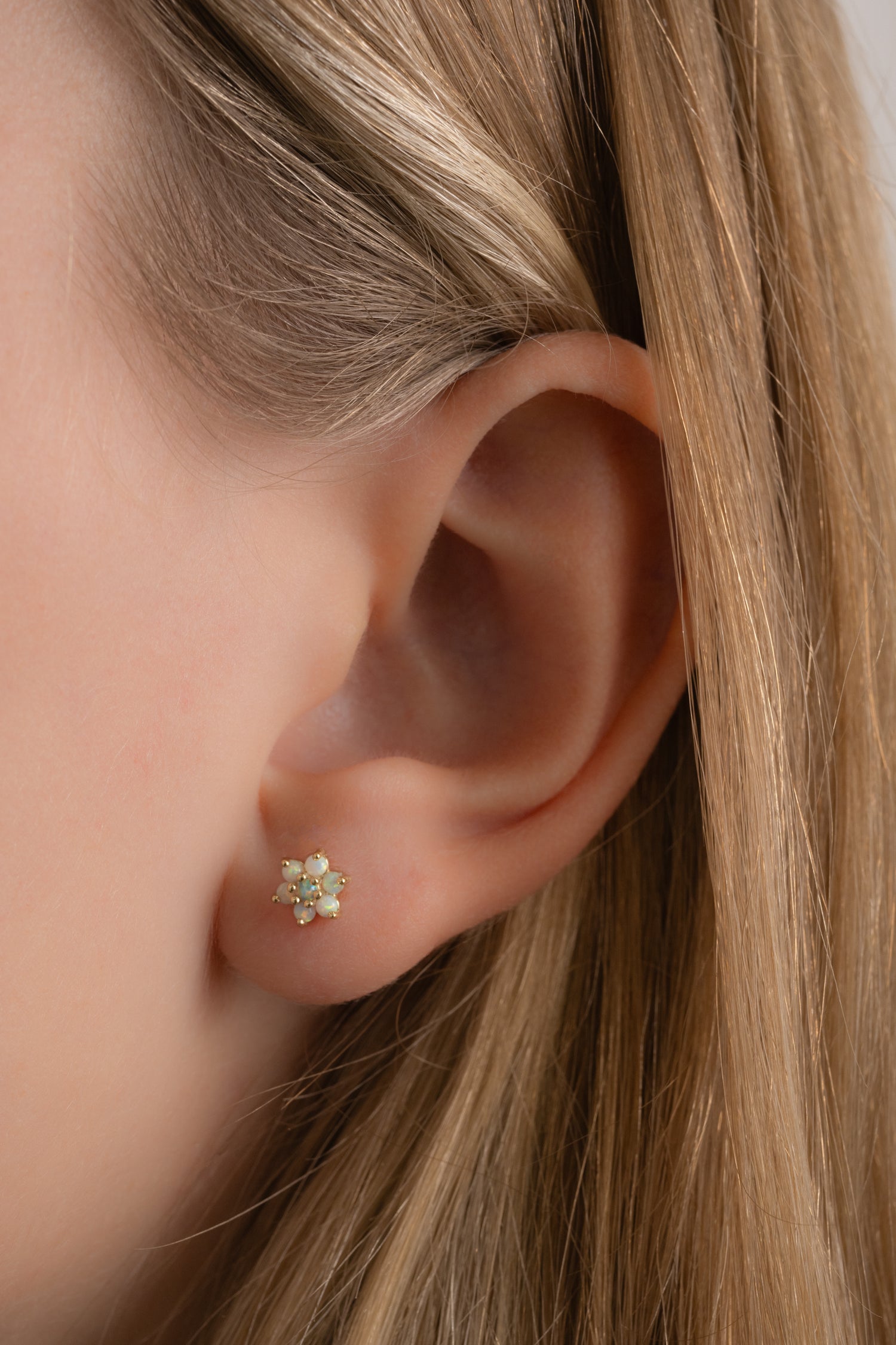 Model wearing dainty gold opal stud earrings.