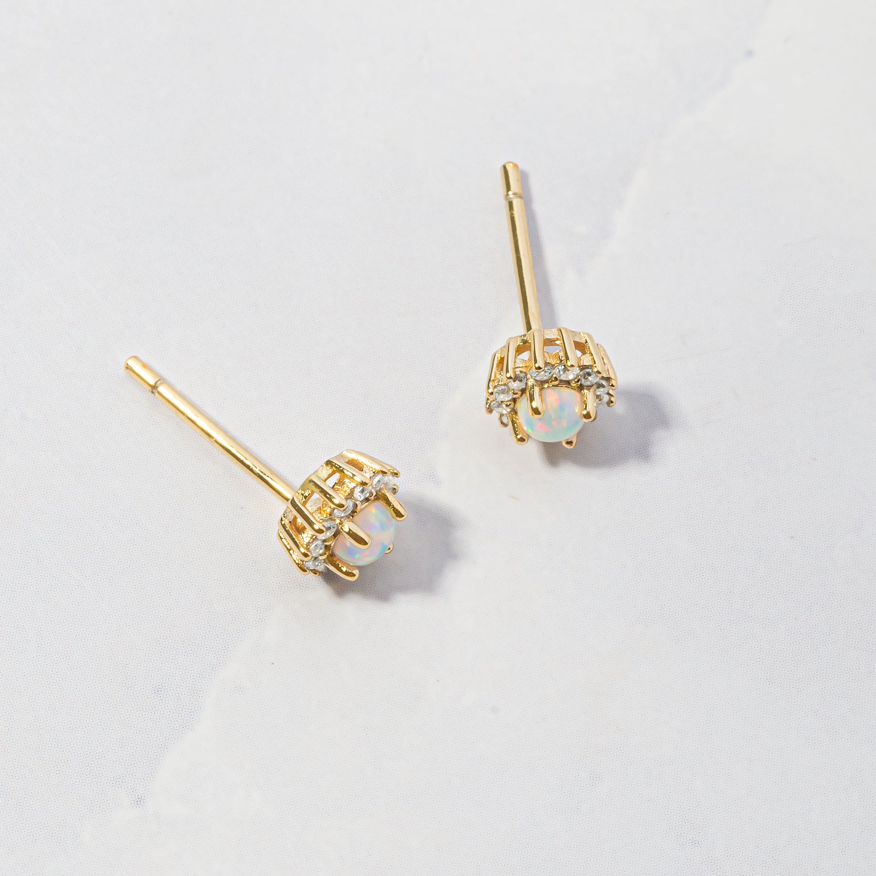 Opal sunburst cz stud earrings from the side angle on marble background. 