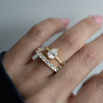 Model wearing gold pear statement stone wedding ring with diamond eternity band. 