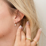 Model wearing gold CZ diamond pearl charm earrings paired with cz huggies. 