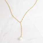 Close-up of pearl lariat necklace with gold thin twisted chain. 