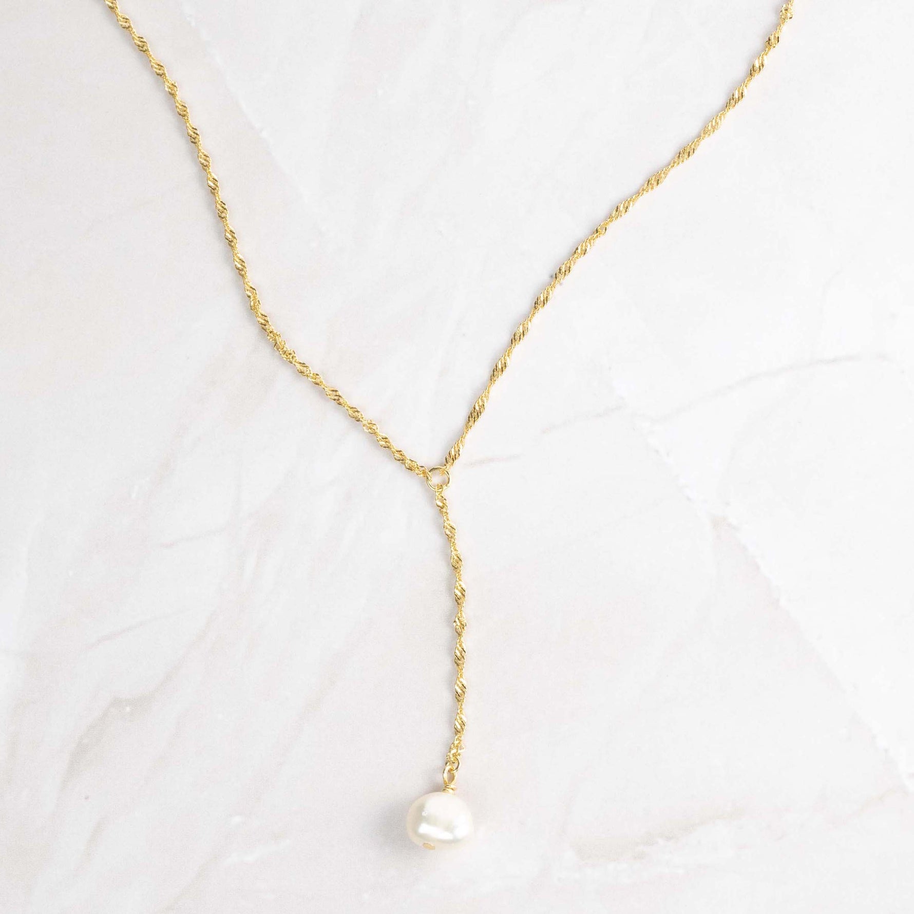 Close-up of pearl lariat necklace with gold thin twisted chain. 