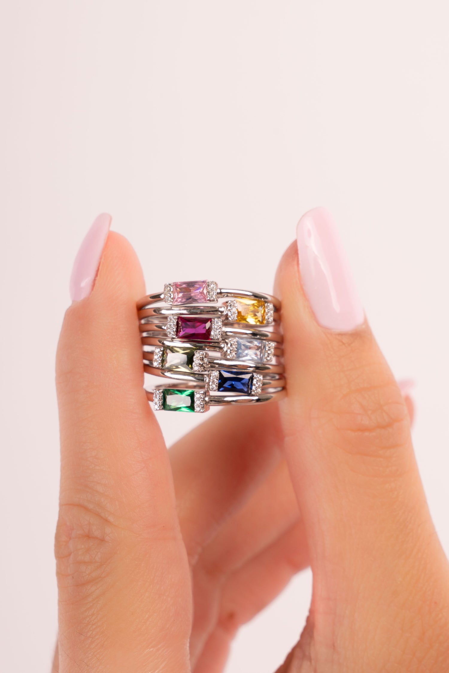 Model holding minimalist silver baguette birthstone rings. 