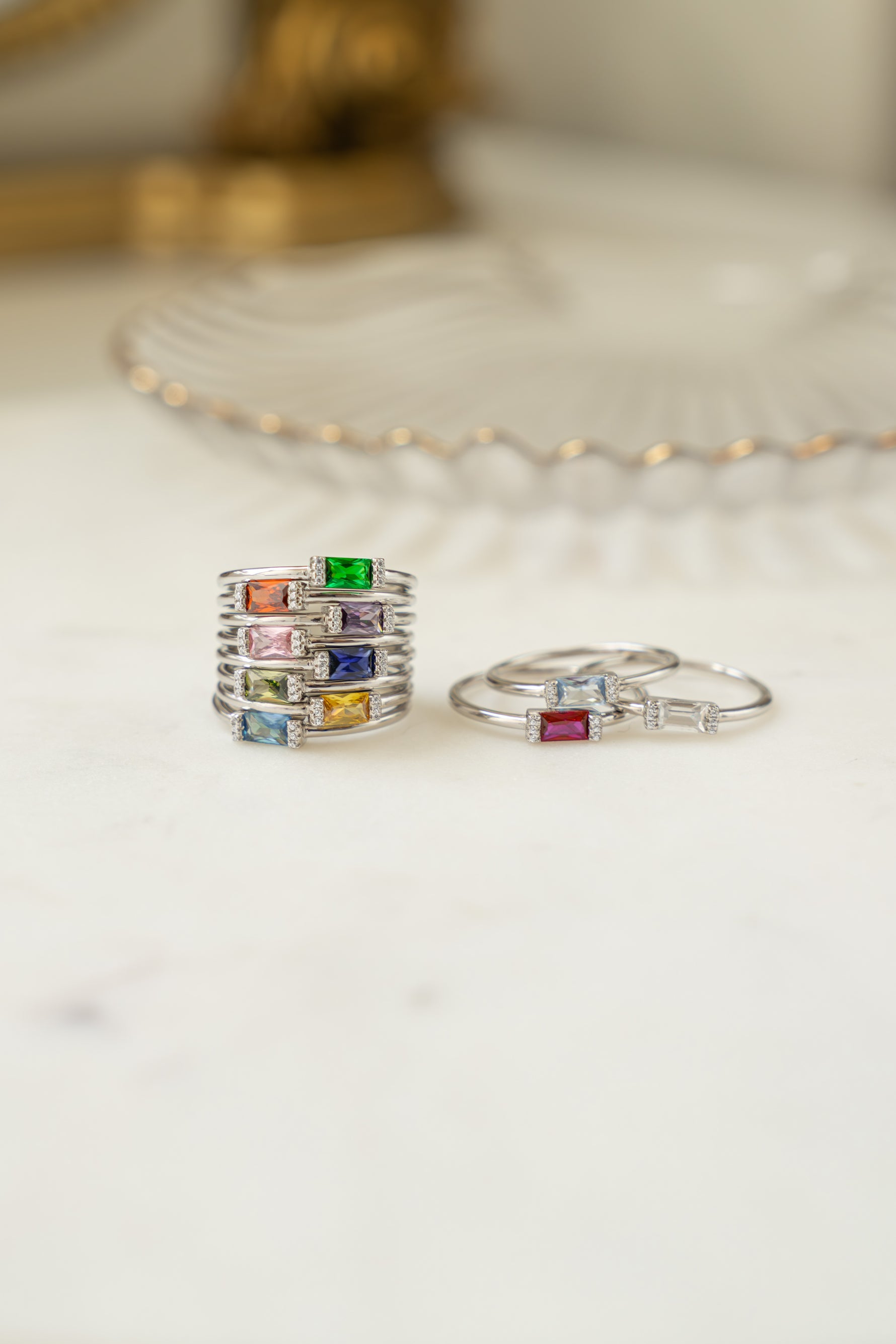 Sterling silver baguette birthstone gem rings in soft studio lighting. 