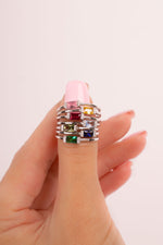Model holding dainty sterling silver birthstone baguette gemstone rings. 