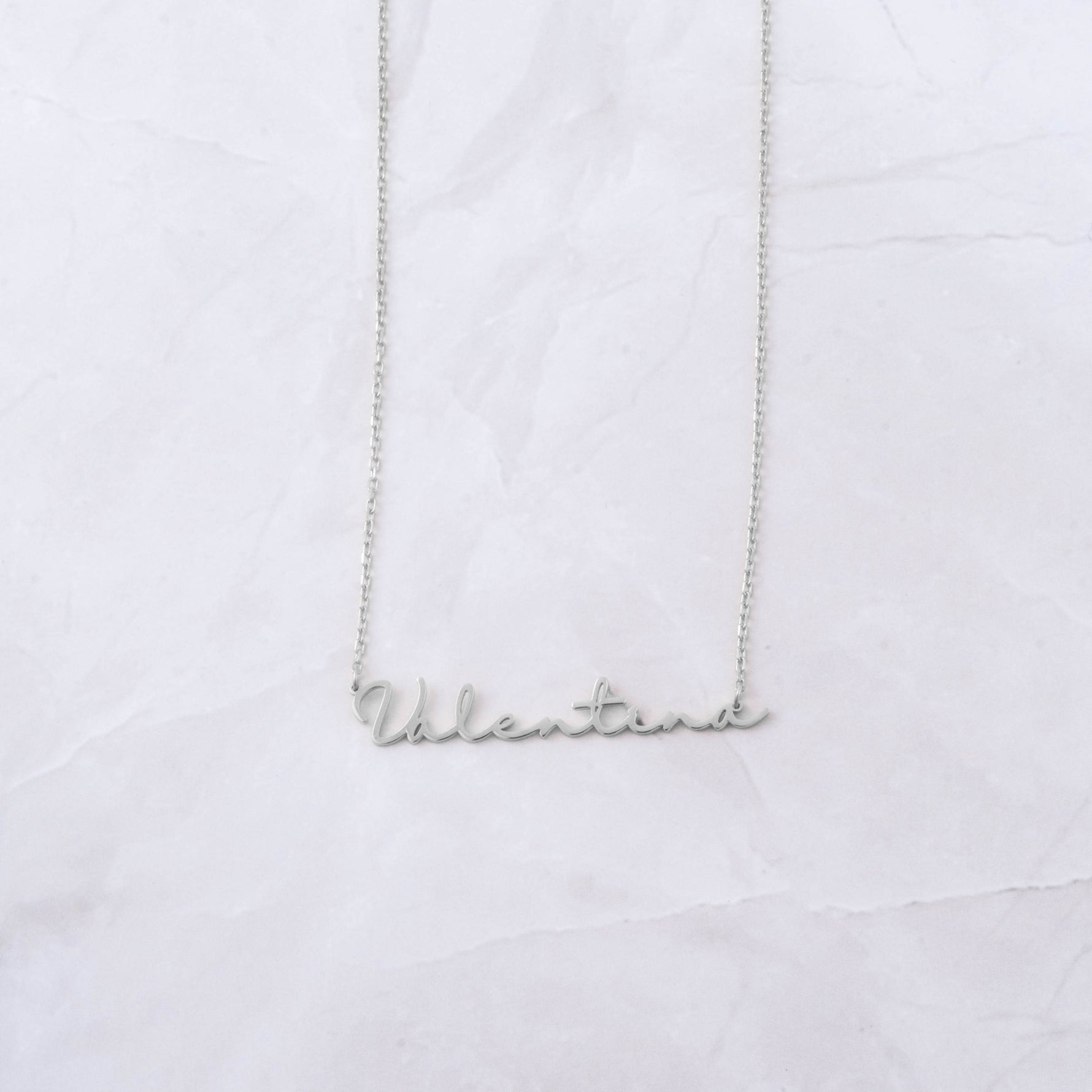 Sterling silver custom script necklace on marble background