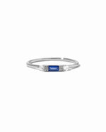 Dainty sterling silver sapphire birthstone stacking baguette ring on white background.