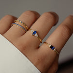 Model wearing trendy gold sapphire gemstone ring stack. 