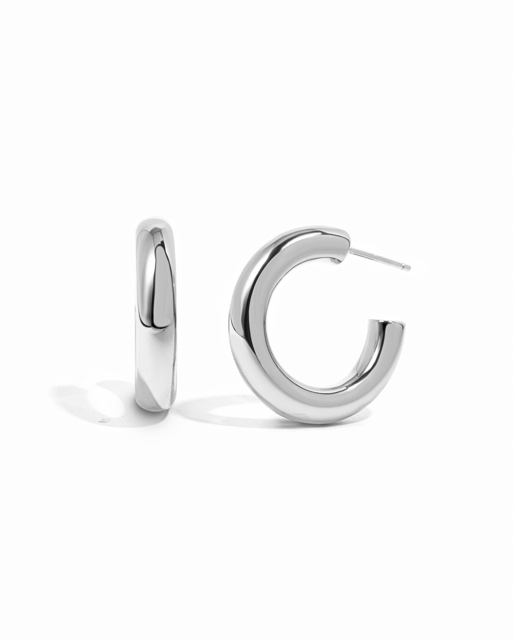 Sleek chunky silver tube hoop earrings on white background